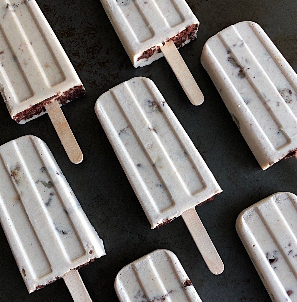 Vegan and paleo chunky monkey tahini roasted banana creamsicles against a black background. 