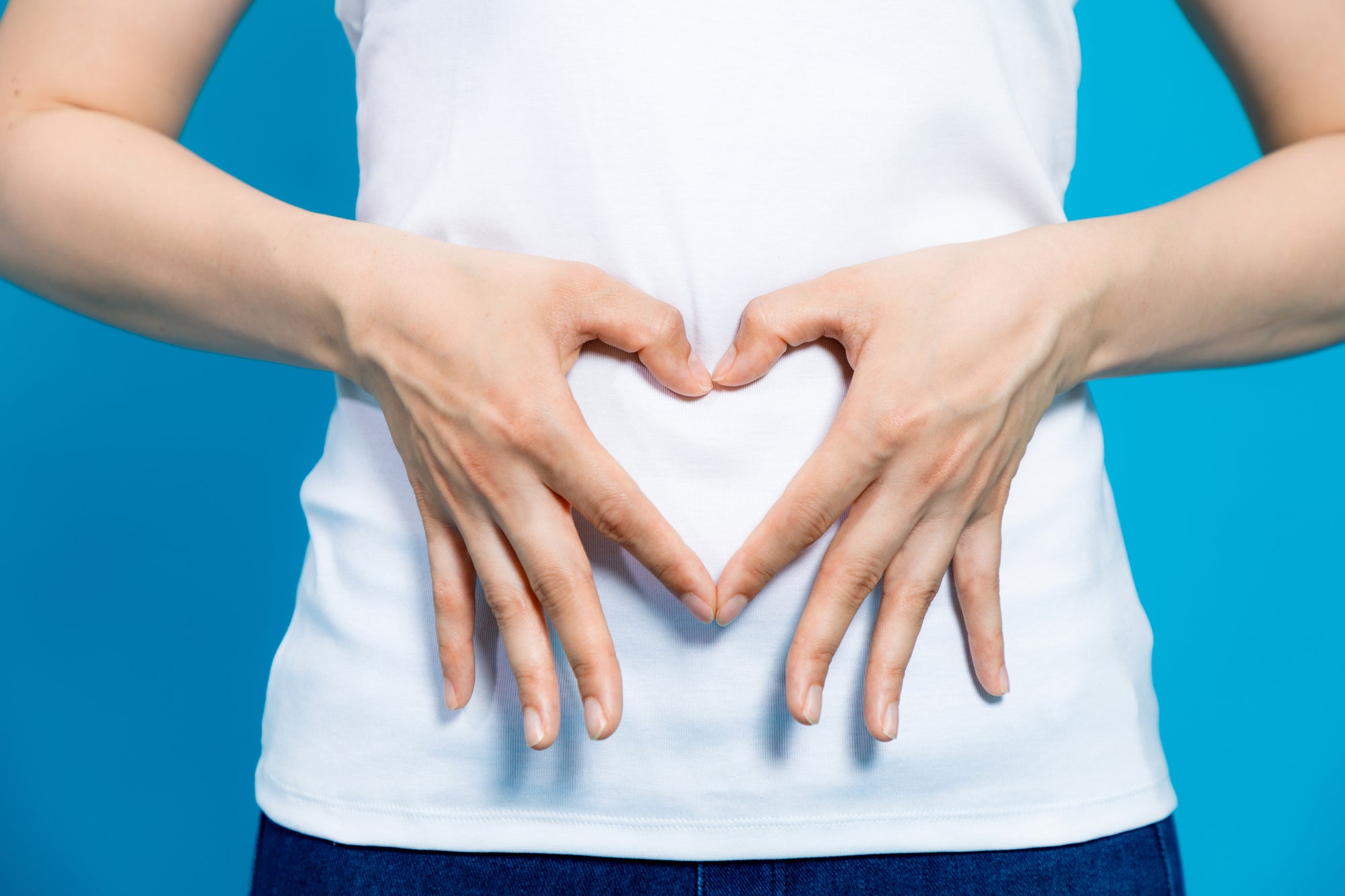 Woman with hands over belly forming a heart