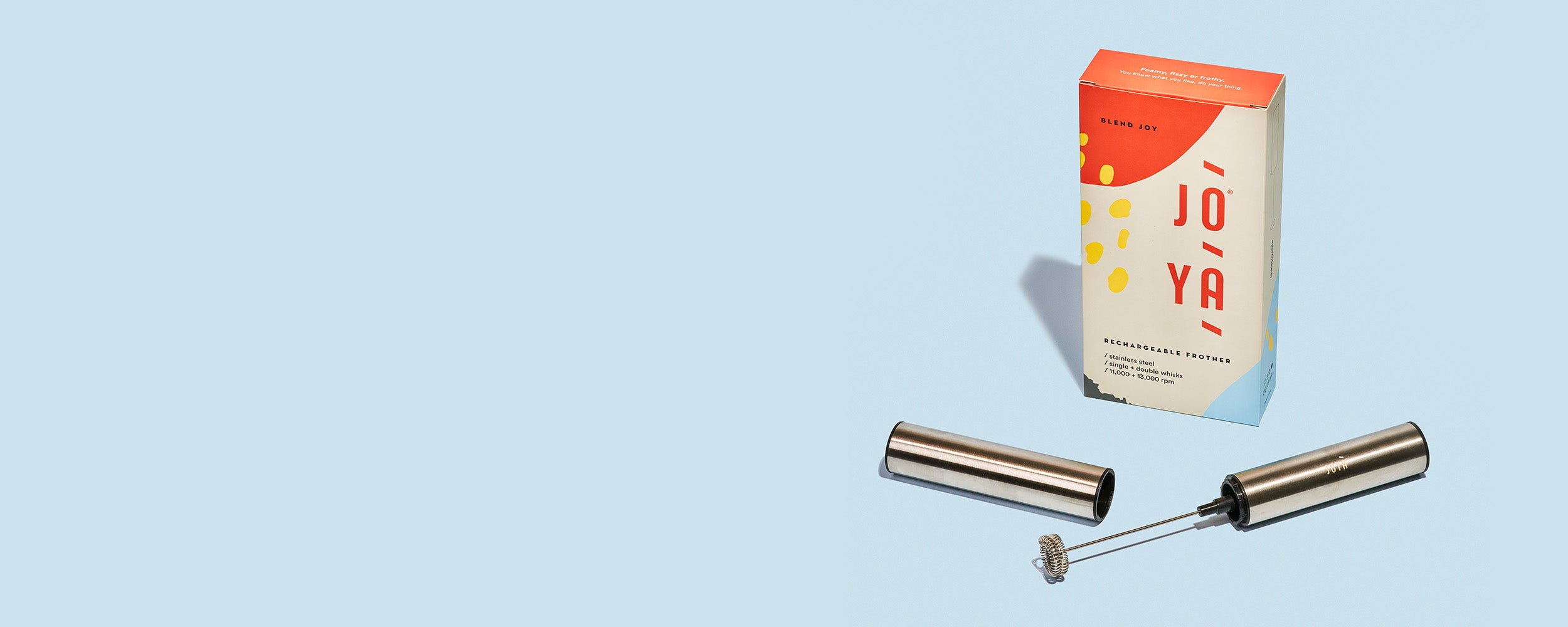 JOYÀ rechargeable handheld frother sitting beside its branded box on a blue background