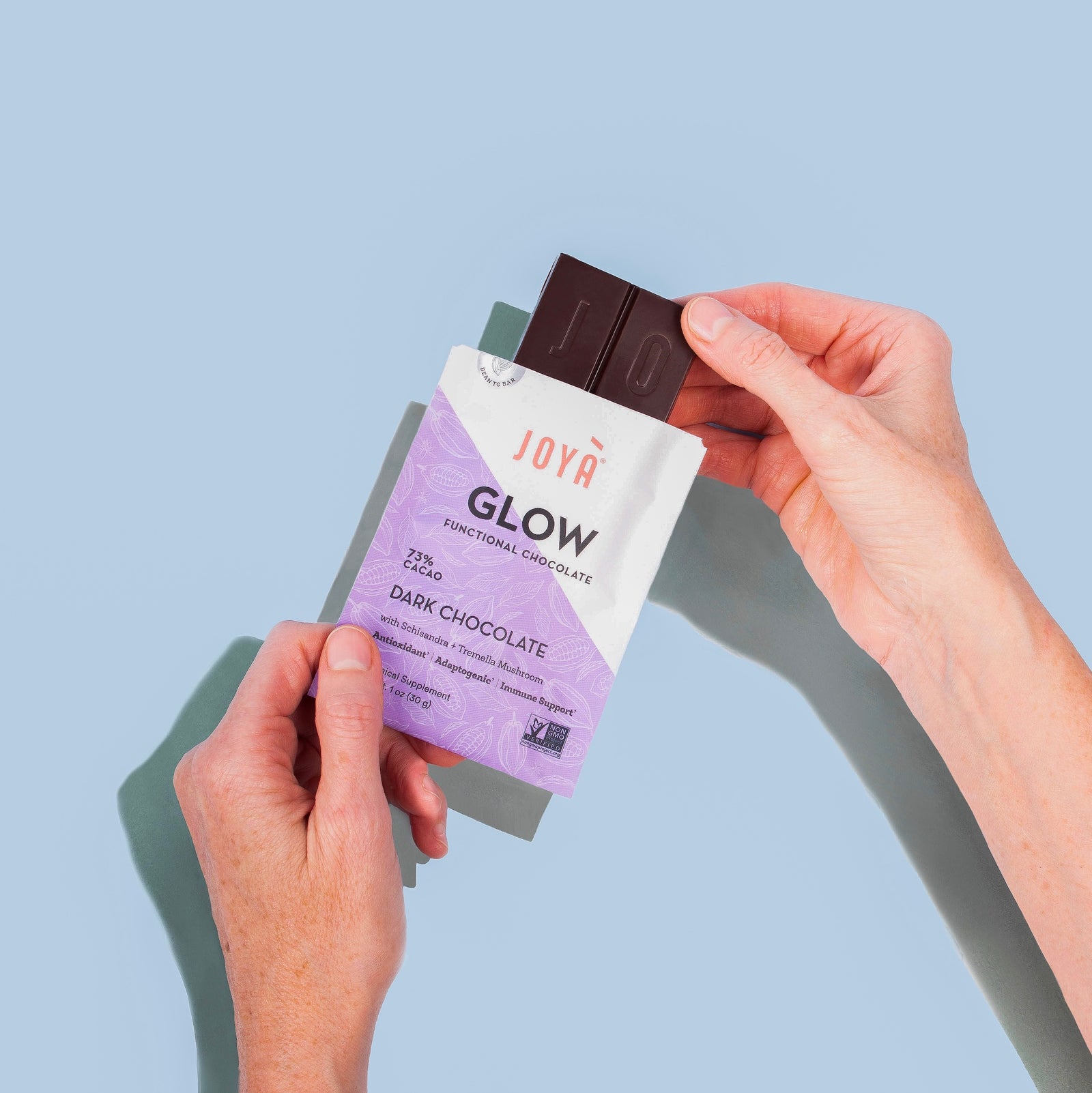 Woman's hands holding a pouch of Glow Chocolate and pulling the bar out of the pouch.