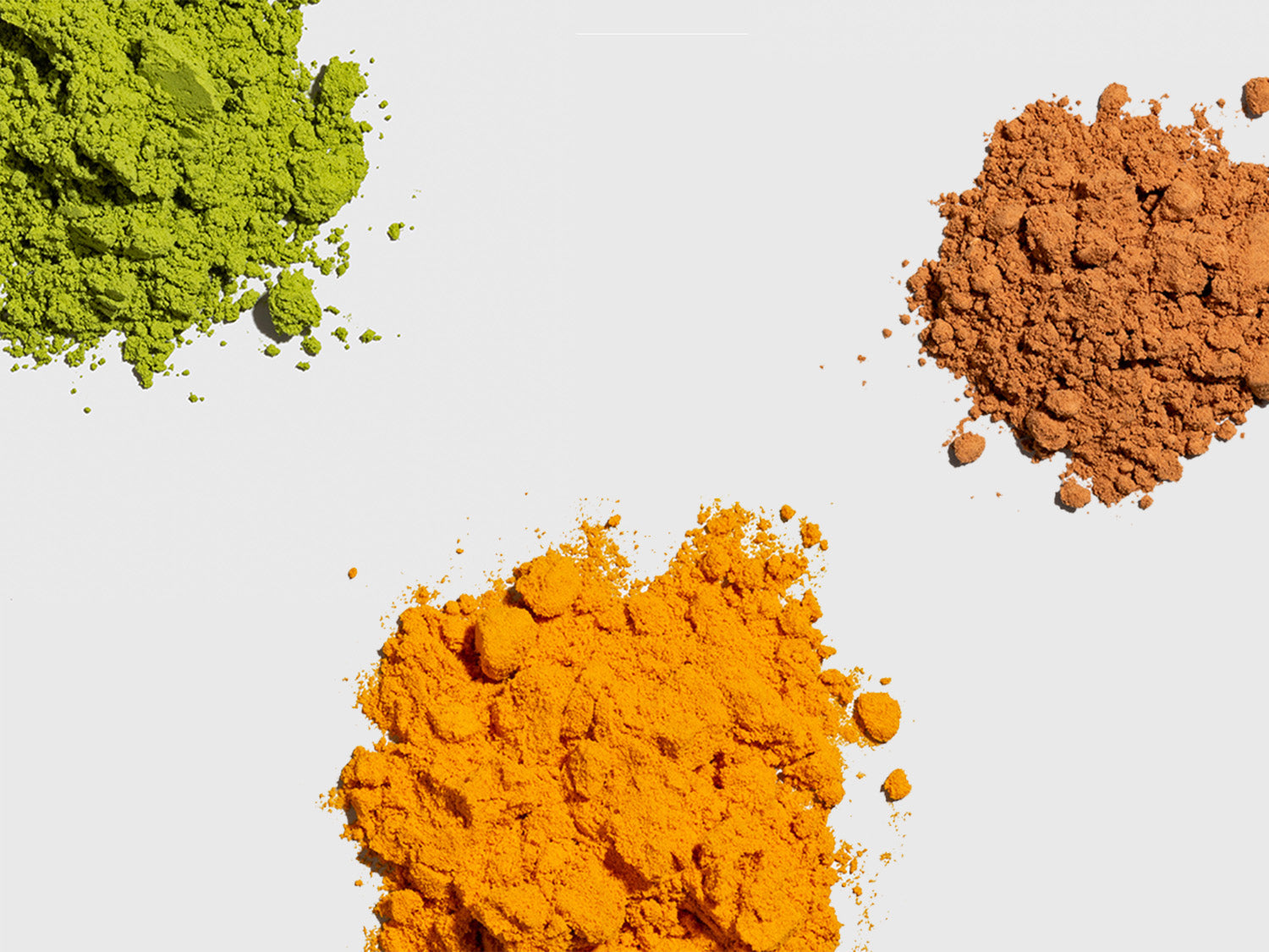 Scoops of matcha, turmeric and cacao powders on a beige background