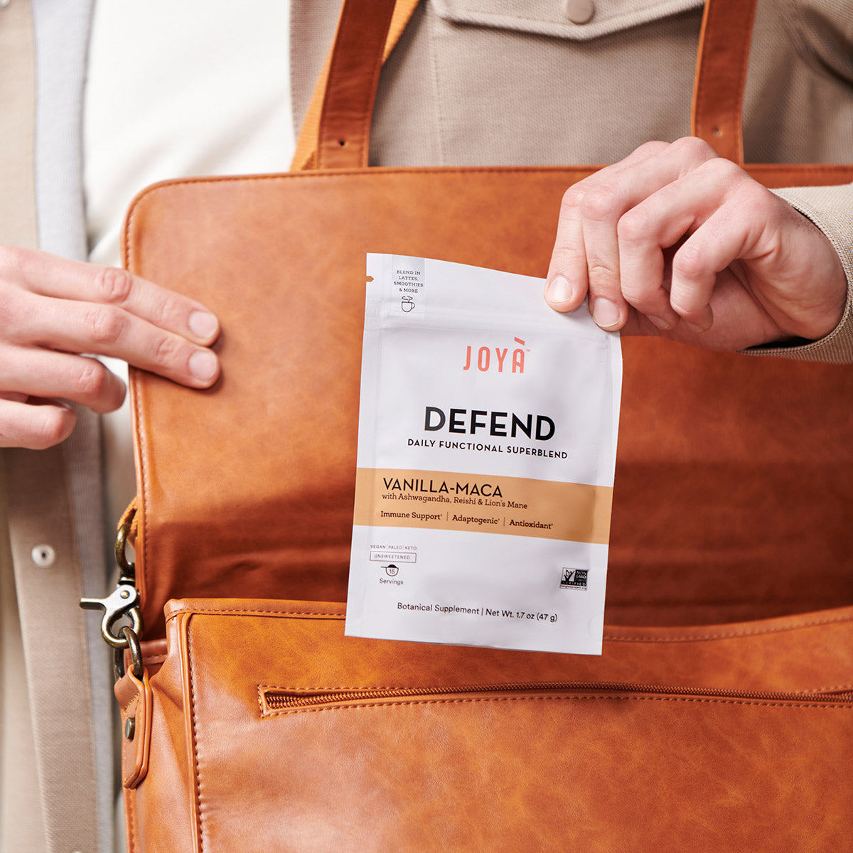 Young man pulling Defend Superblend 15-serving pouch out of his leather work bag