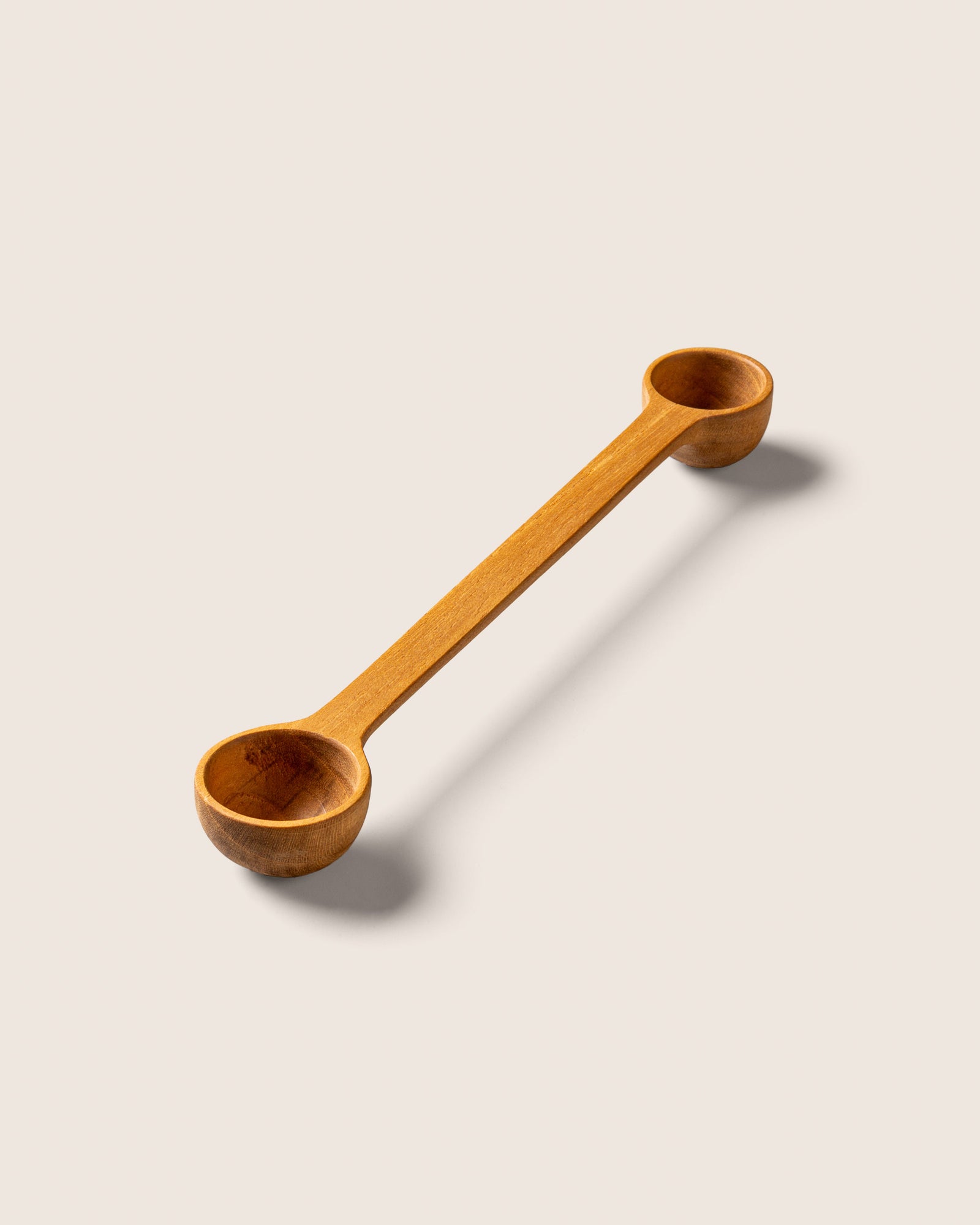 Handcrafted wooden spoon sitting on a beige tabletop
