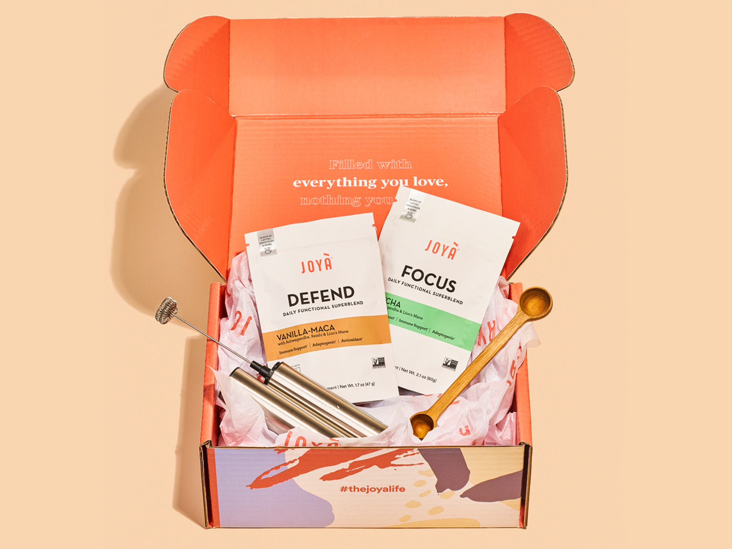 JOYÀ Subscription Starter Bundle with Defend and Focus Superblend 15-serving pouches, rechargeable frother and wooden spoon in a branded box on a beige background