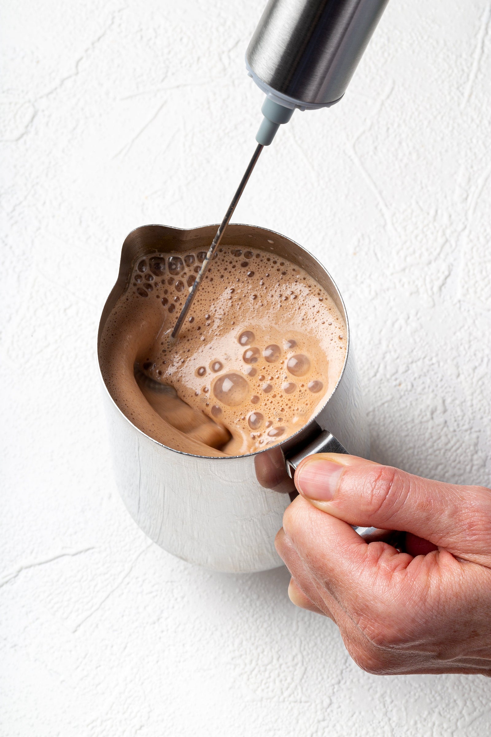 Blending a hot cacao elixir with a JOYÀ handheld rechargeable milk frother and blender.