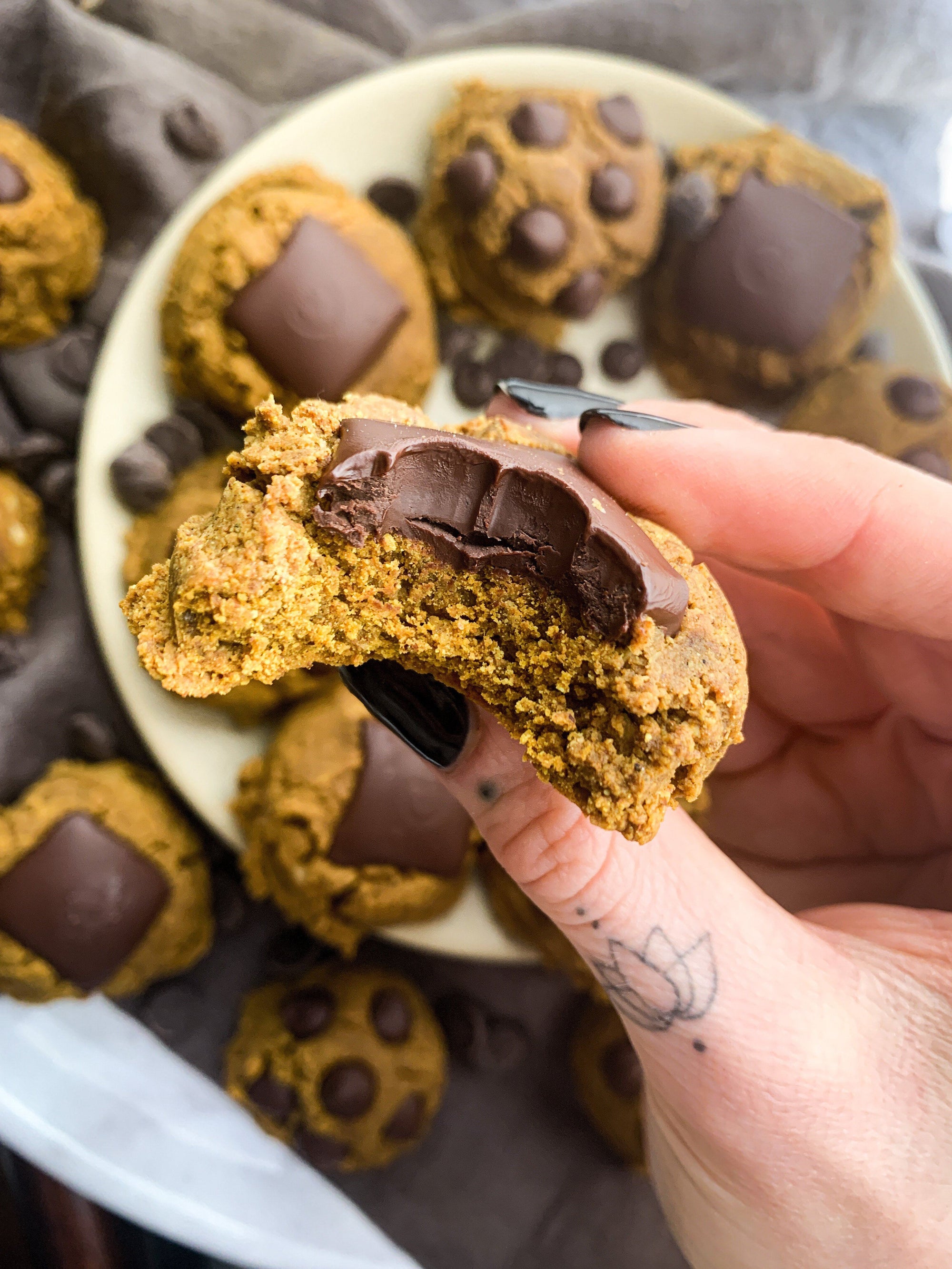 Hand holding a Golden Vanilla Chai Cookie with chocolate chunks