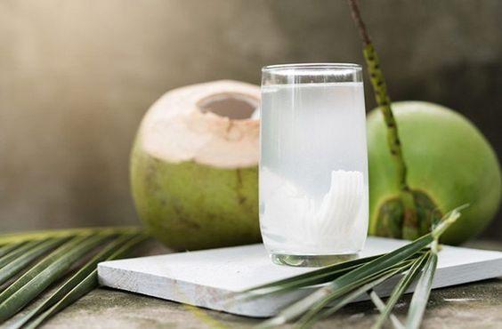 coconut water on marble slab with coconuts in background