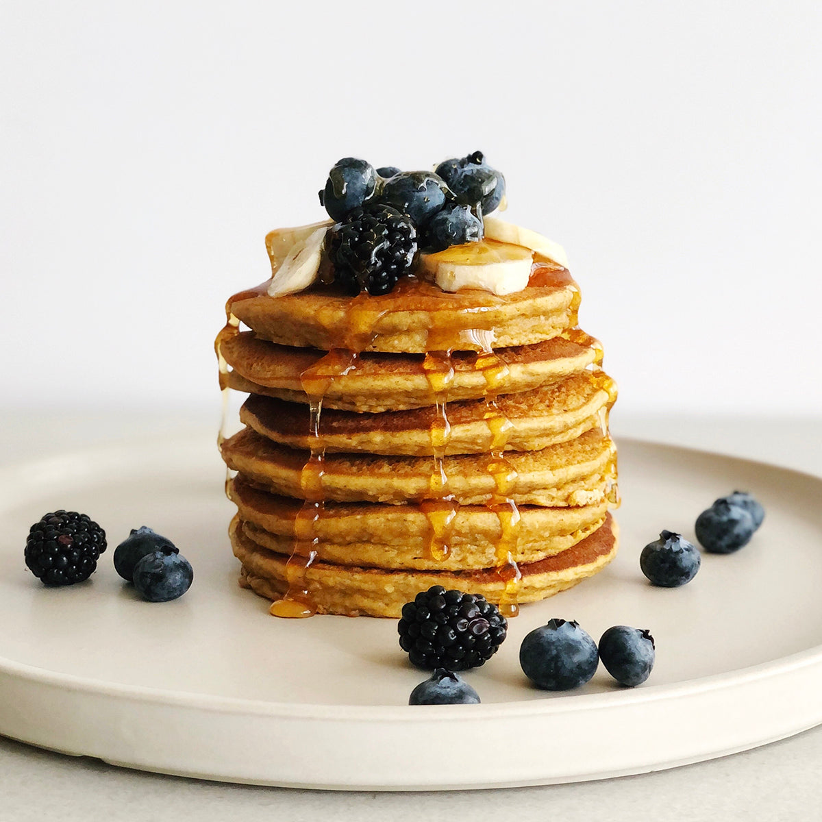 Stack of pancakes topped with bananas, blueberries and maple syrup 
