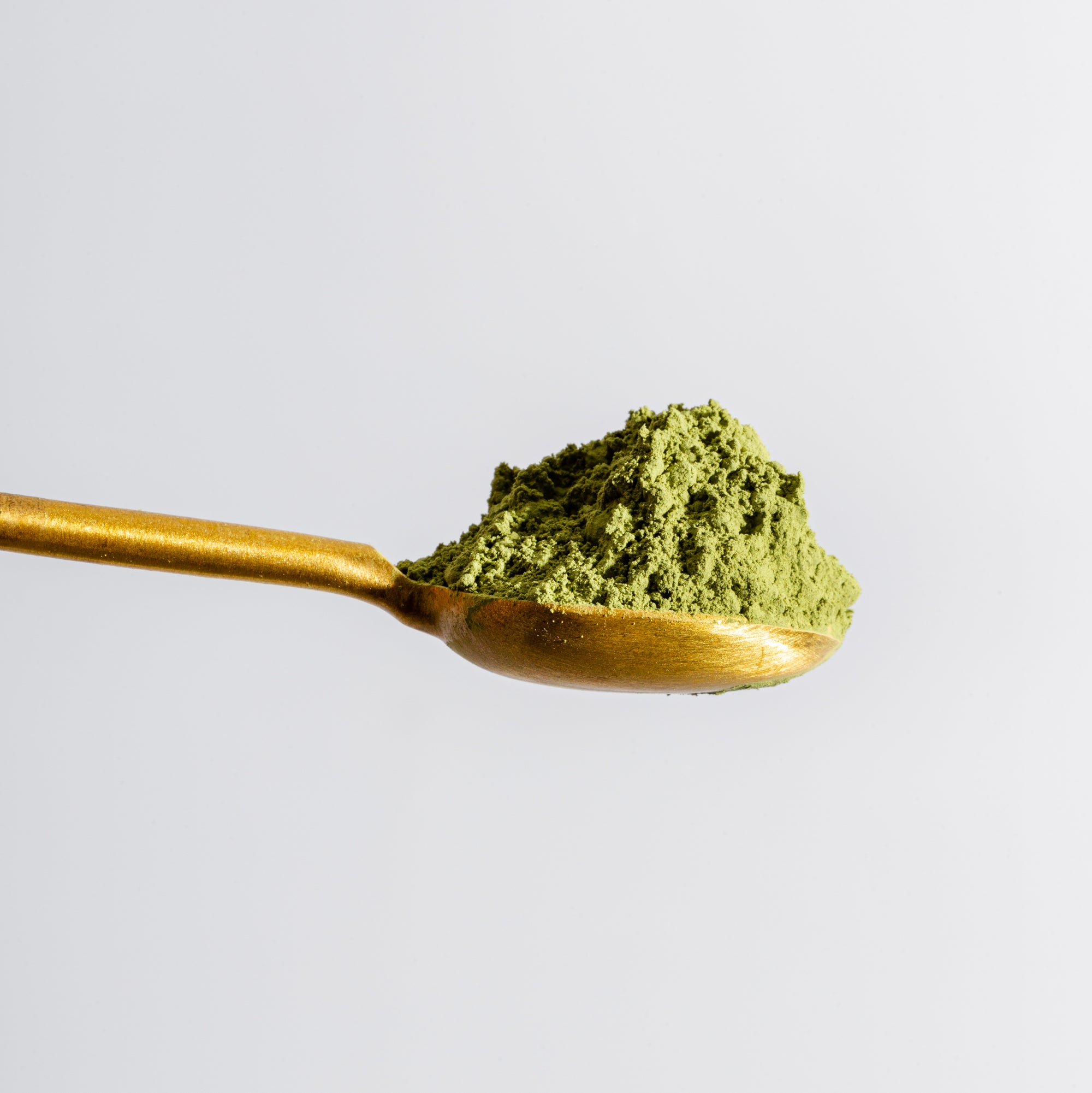 Gold metal spoon with green matcha powder