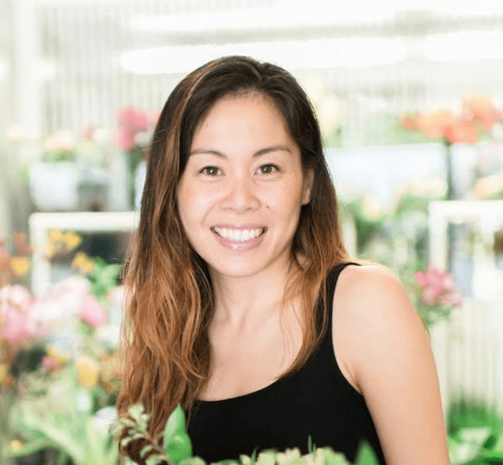 A young asian woman, Jamie Hengartner, smiles in a flower shop.