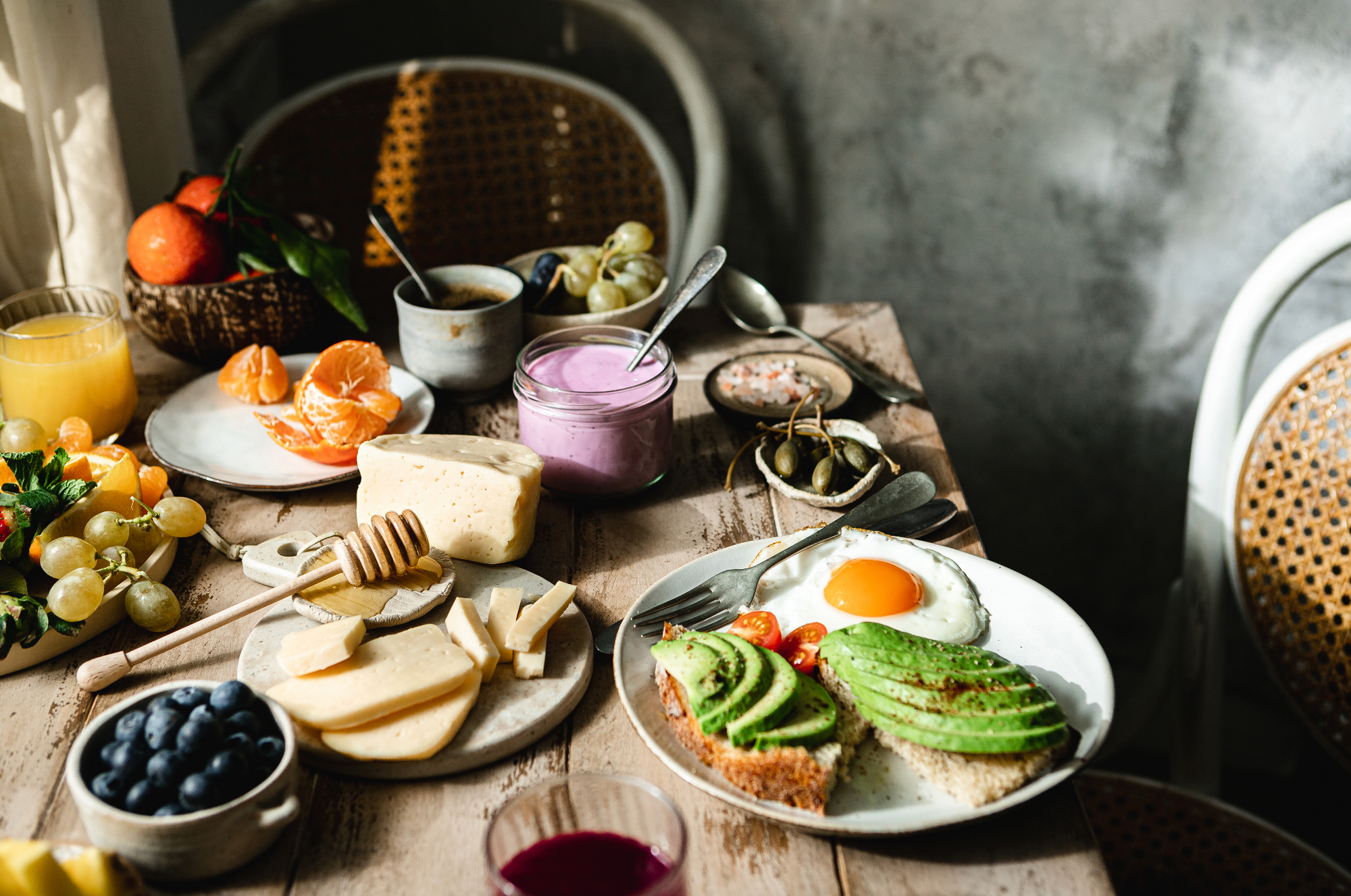 Rustic style table with breakfast foods featuring a smoothie, eggs, avocado and blueberries