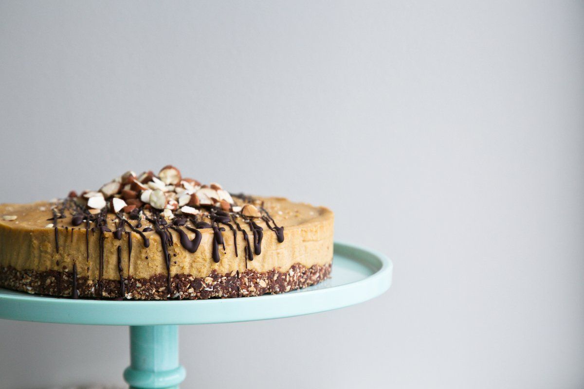 raw almond cake on a mint green cake stand, drizzled with chocoalte