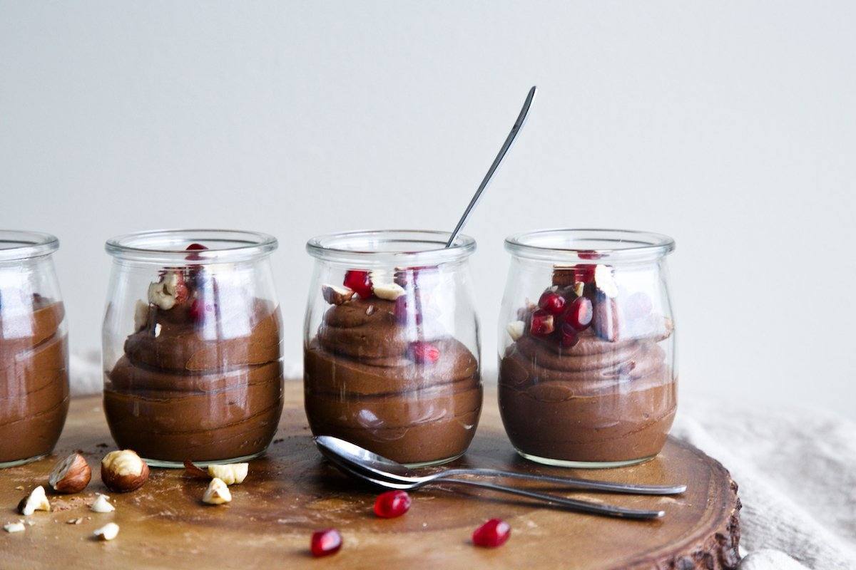 mexican chocolate mouse in small glass cups garnished with hazelnut and pomegranate seeds