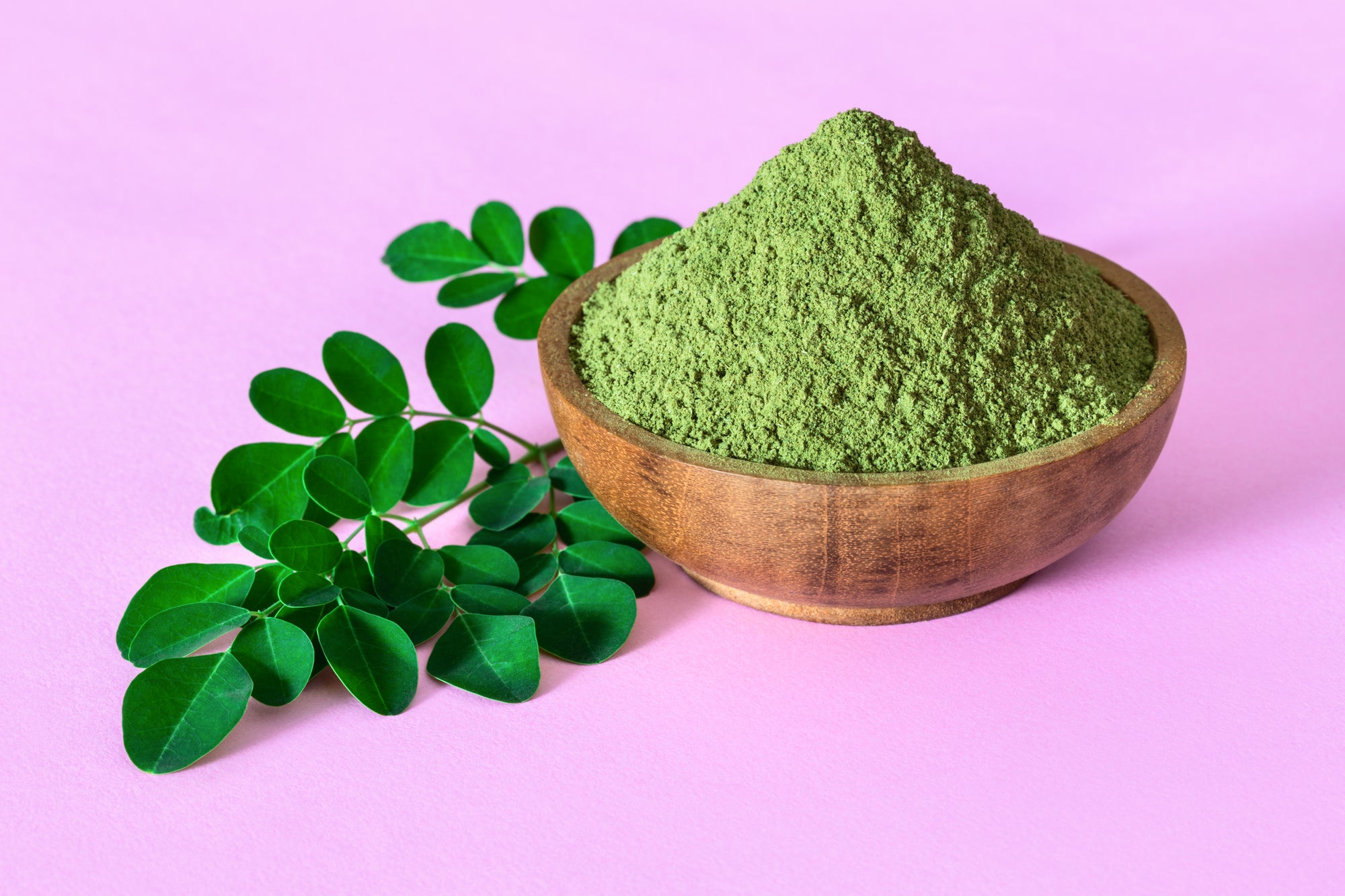 Moringa leaf and moringa leaf powder in a wooden bowl