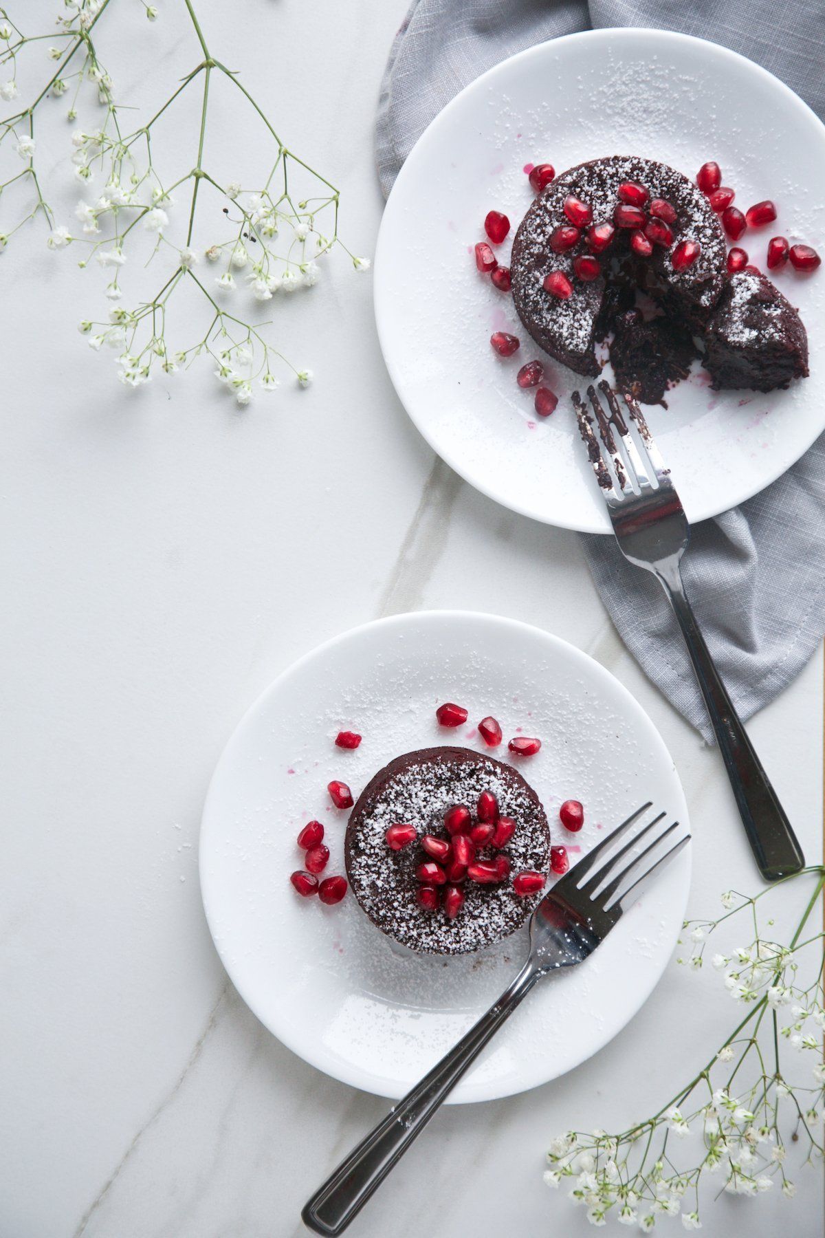 two plated red velvet chocolate lava cakes garnished with pomegranate