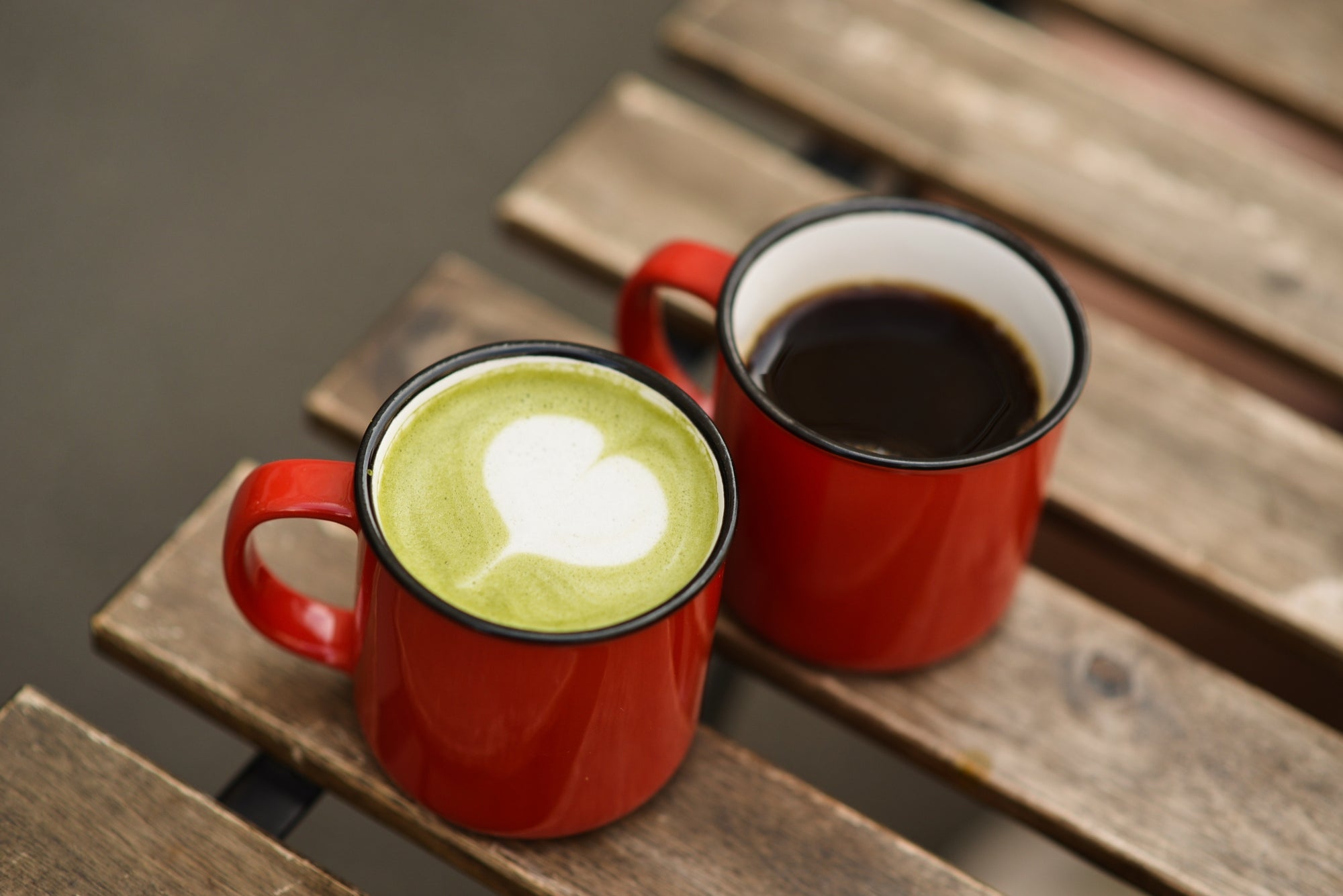 Two red mugs with a matcha latte and a brewed coffee