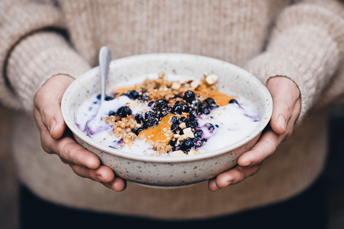 winter breakfast bowl held by two hands in a cozy sweater