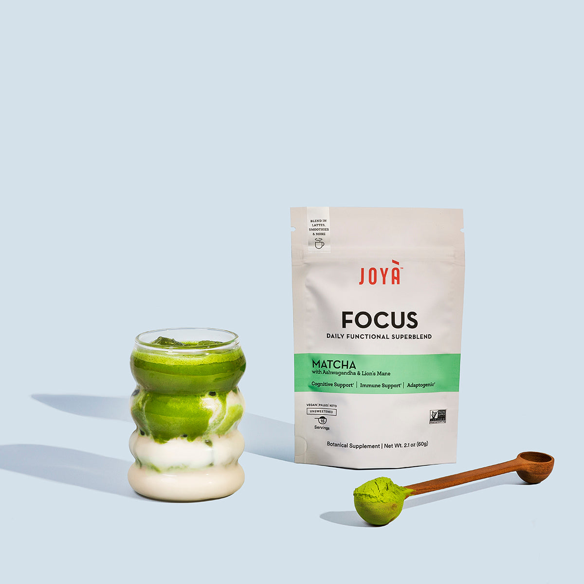 Focus Superblend 15-serving pouch beside a wooden spoon and an iced Focus matte latte in a clear glass